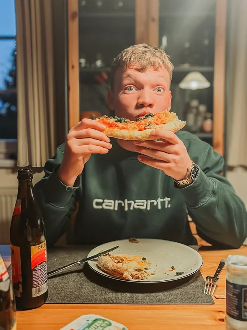 Bjarne beißt genüsslich in ein Stück selbstgemachte Pizza