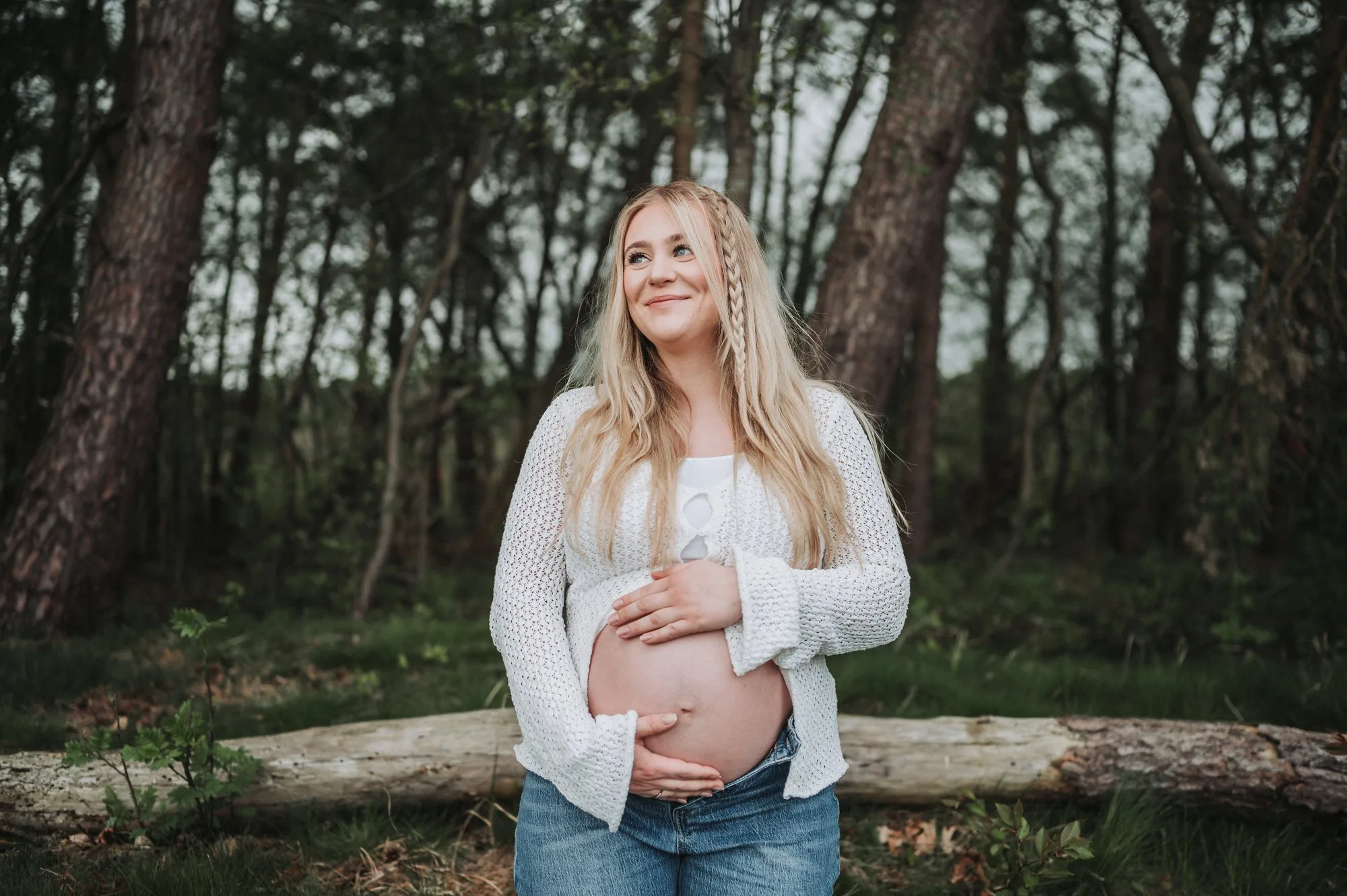 Schwangere Frau hält ihren Babybauch im Wald bei einem Babybauchshooting in Dithmarschen
