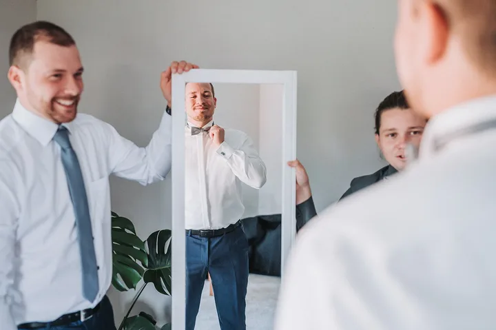 Bräutigam macht sich beim Getting Ready vor dem Spiegel fertig