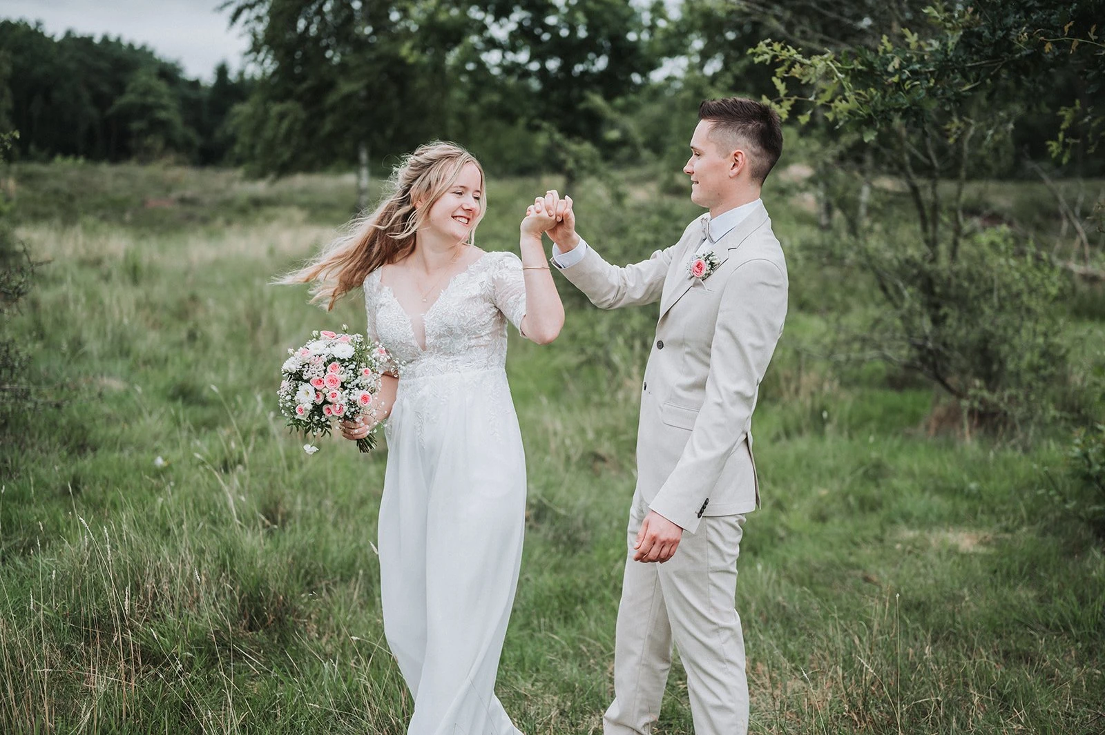 Brautpaar tanzt lachend über eine Wiese bei einer Hochzeit in Marne